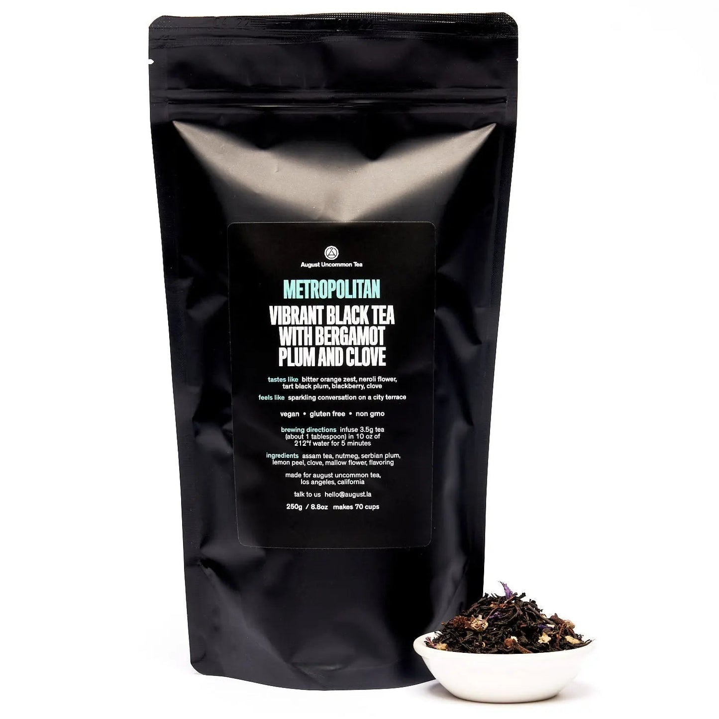Black Metropolitan tea pouch with label, with a small bowl of tea leaves