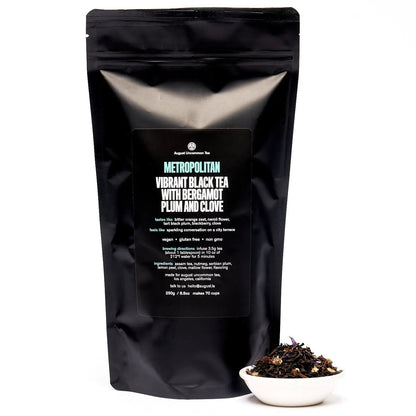 Black Metropolitan tea pouch with label, with a small bowl of tea leaves