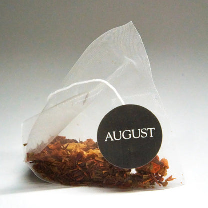 Roasted tea bag pouch filled with dried tea leaves, sealed with AUGUST logo