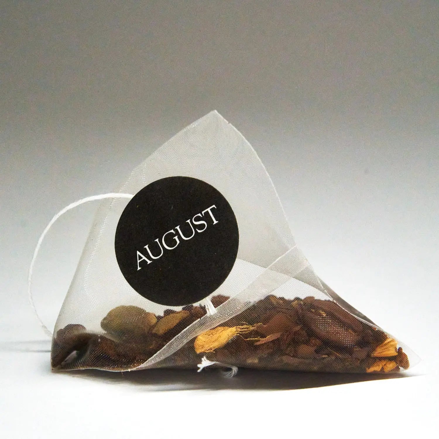 Mesh tea bag filled with spiced black tea leaves and visible spices