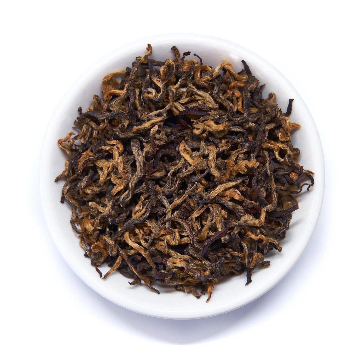 Black tea leaves, loose tea in white bowl with brown and gold tones