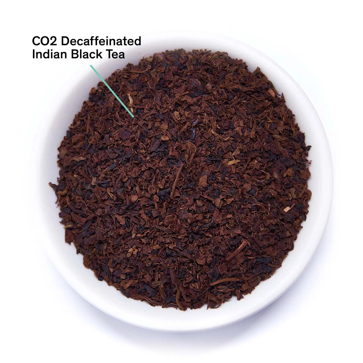 Loose dark brown decaf black tea leaves in white bowl