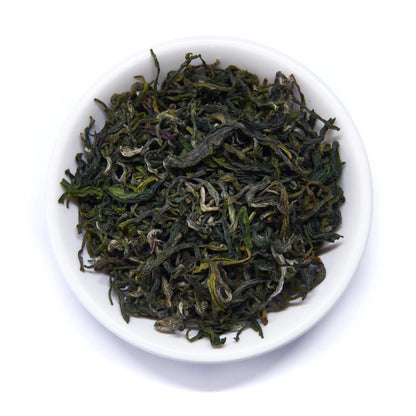 Emerald green tea leaves in a white round dish