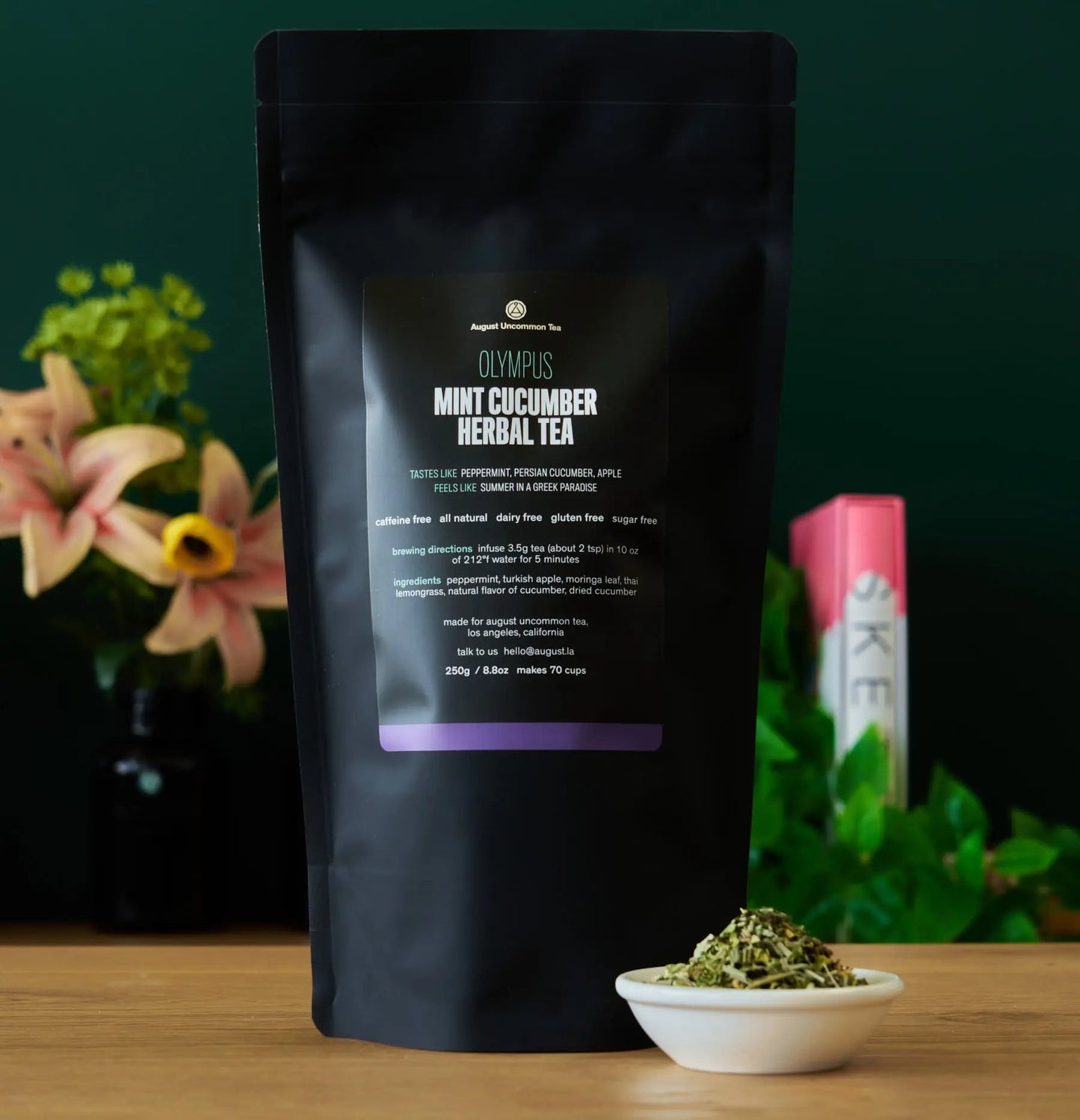 Black herbal tea pouch shown from back with bowl of dried tea leaves