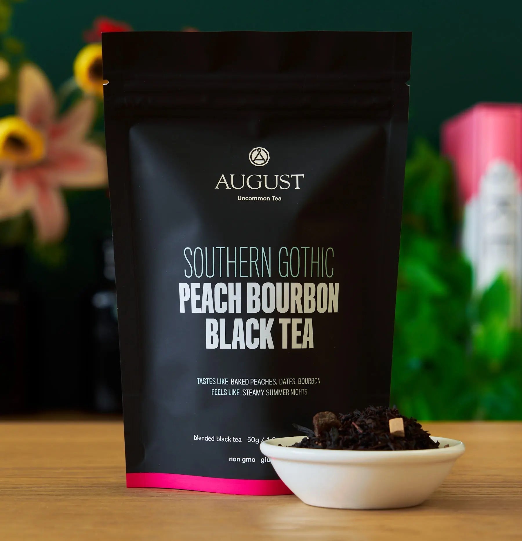 Black tea pouch with pink stripe, plus small bowl of dark tea leaves on table