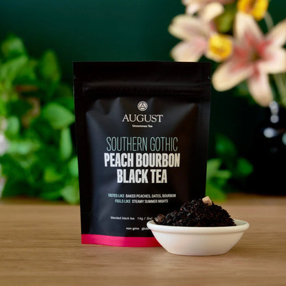 Black tea pouch with pink stripe beside a white bowl of dark tea leaves