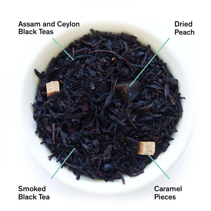 Bowl of loose black tea leaves with labeled blend pieces and dried peach accents