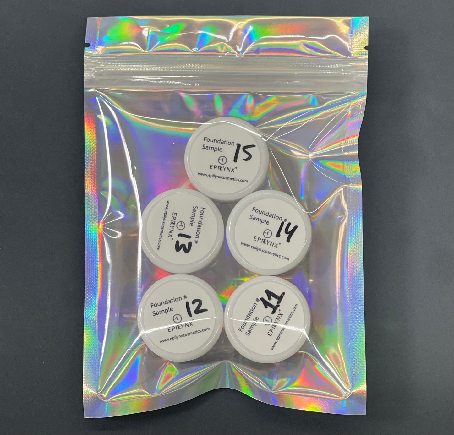 Foundation sample set with five circular lids in a holographic pouch.