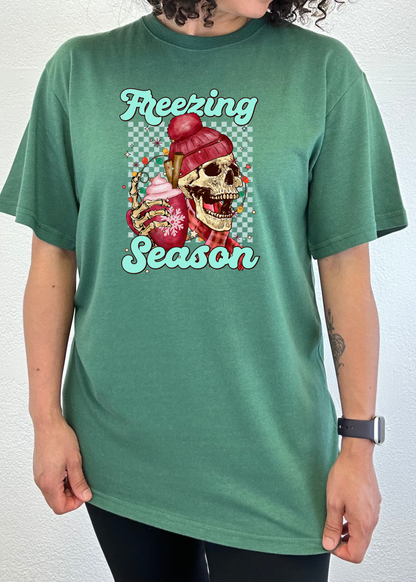 Teal green short sleeve T-shirt with “Freezing Season” skull graphic on chest.