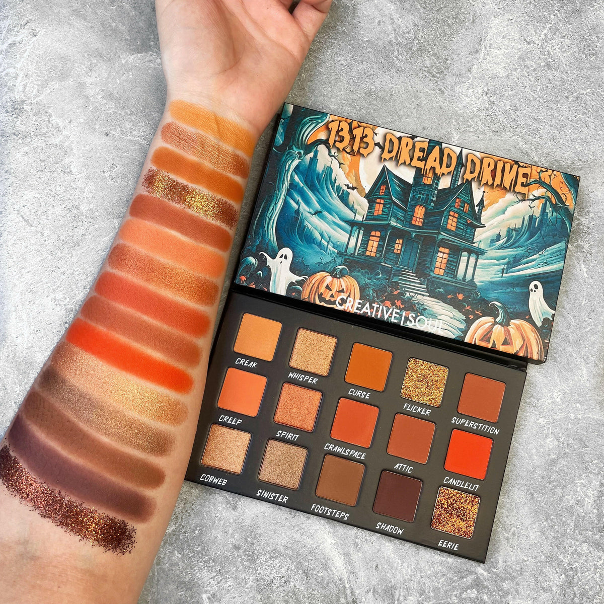 Eyeshadow palette with 16 pans and a swatch strip in orange-gold shimmer and brown
