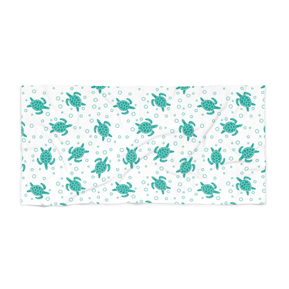 Beach towel with teal sea turtle pattern on white, rectangular folded layout