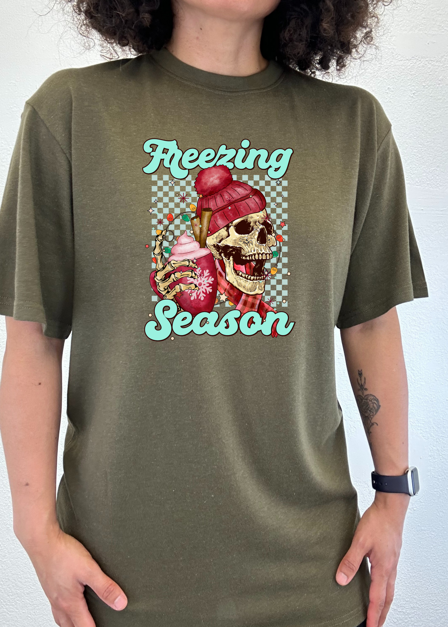 Olive green short sleeve T-shirt with “Freezing Season” skull graphic on chest.