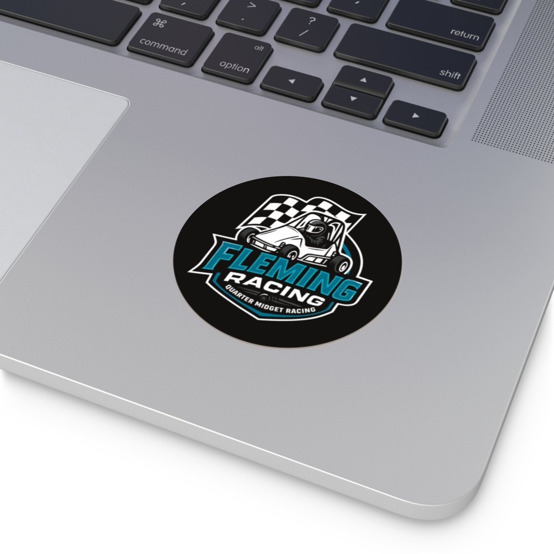 Round black vinyl logo sticker on a laptop lid with Fleming Racing checkered car design