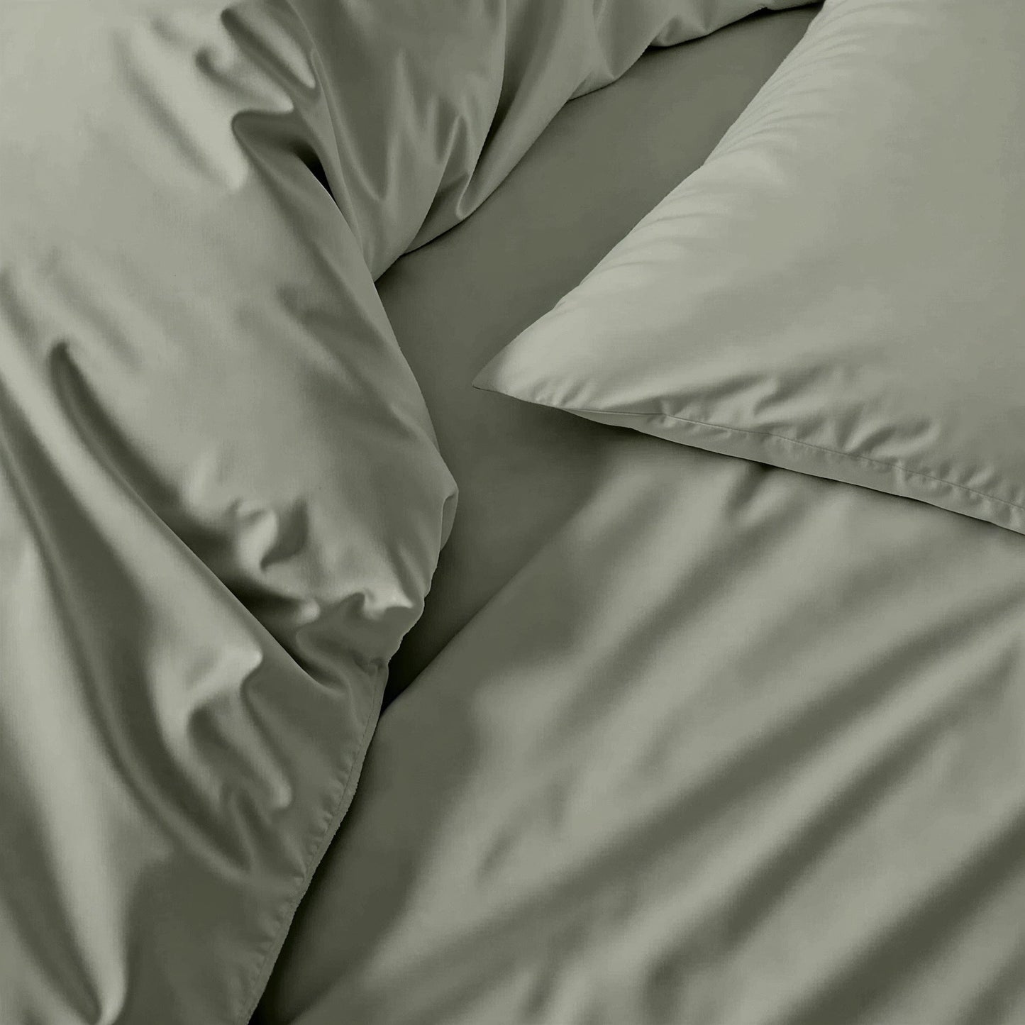 Sateen sheet set fabric in sage green, close-up of bed linens and pillow edge