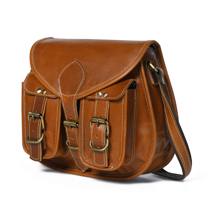 Brown leather womens sling bag close-up with flap, stitched seams, and front buckle pockets