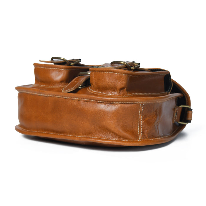 Brown leather sling bag side profile with top handles and metal hardware buckles