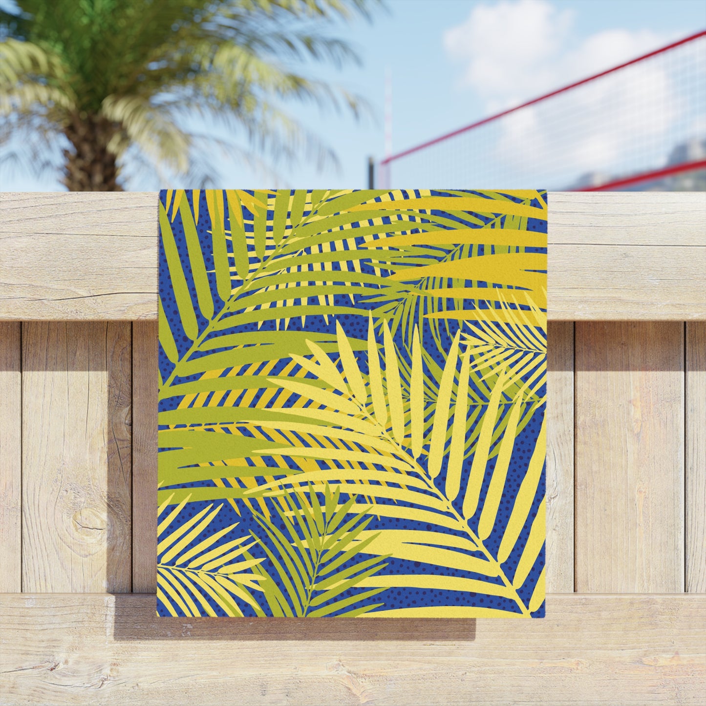 Beach towel with bold palm leaf print on yellow fabric in blue tones