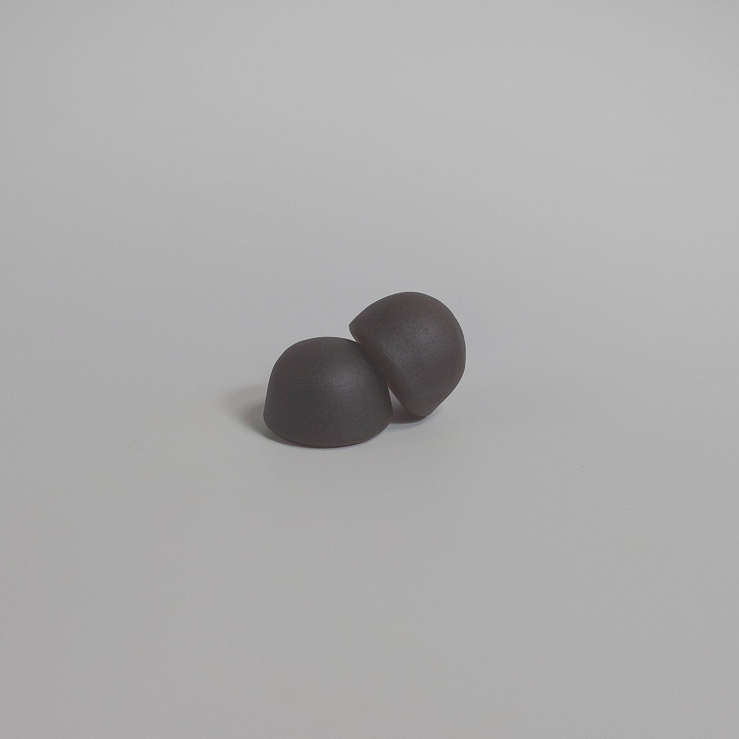Dark mushroom gummies, two rounded pieces on a plain light gray surface