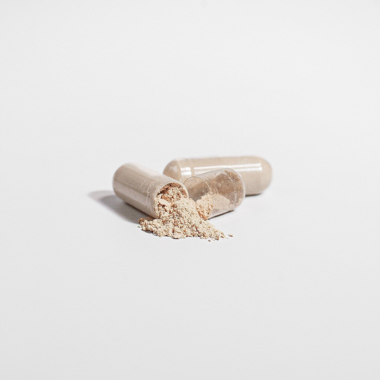 Chaga mushroom capsules with powder scattered on a white background.