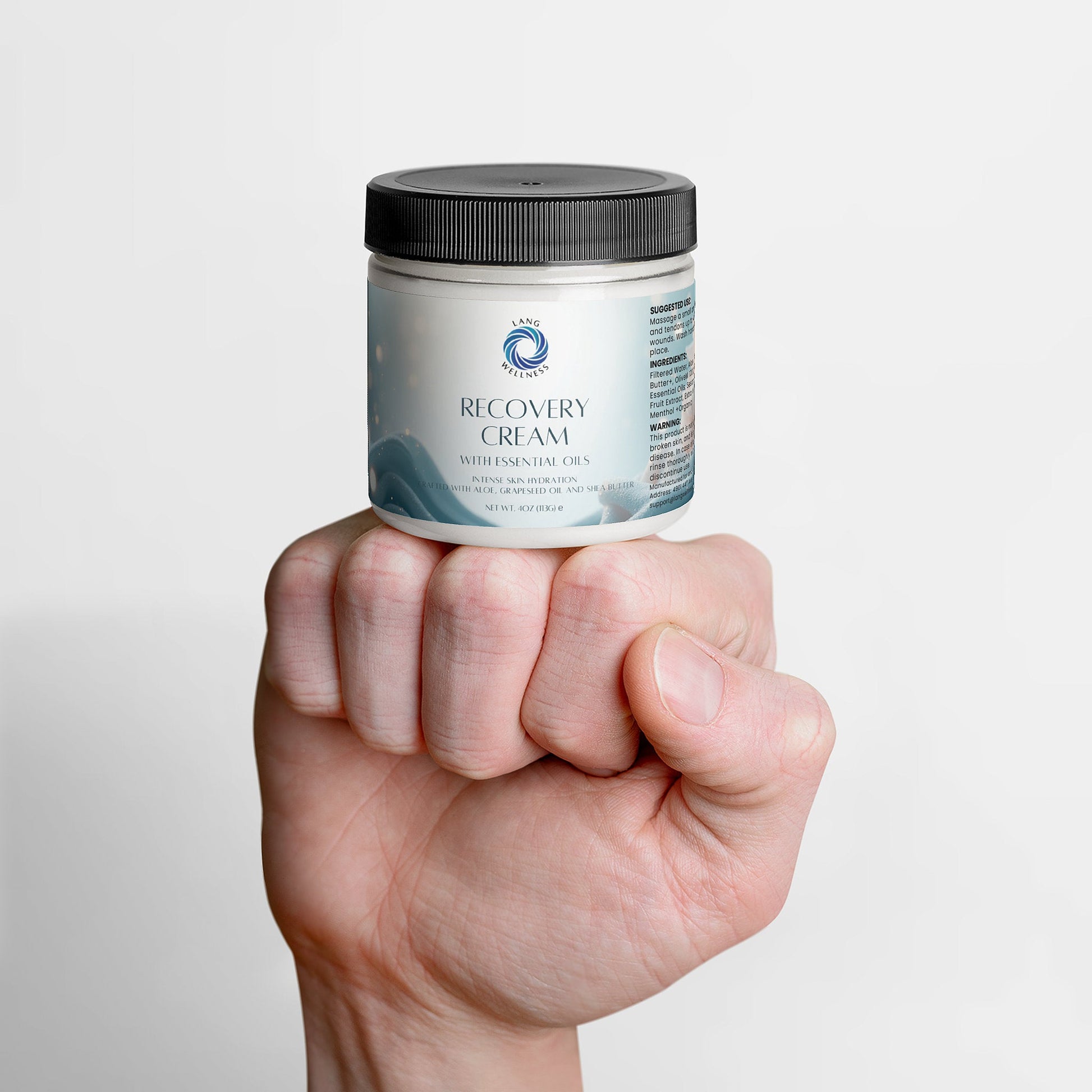 Recovery cream jar held in one hand, black lid on top and label facing outward