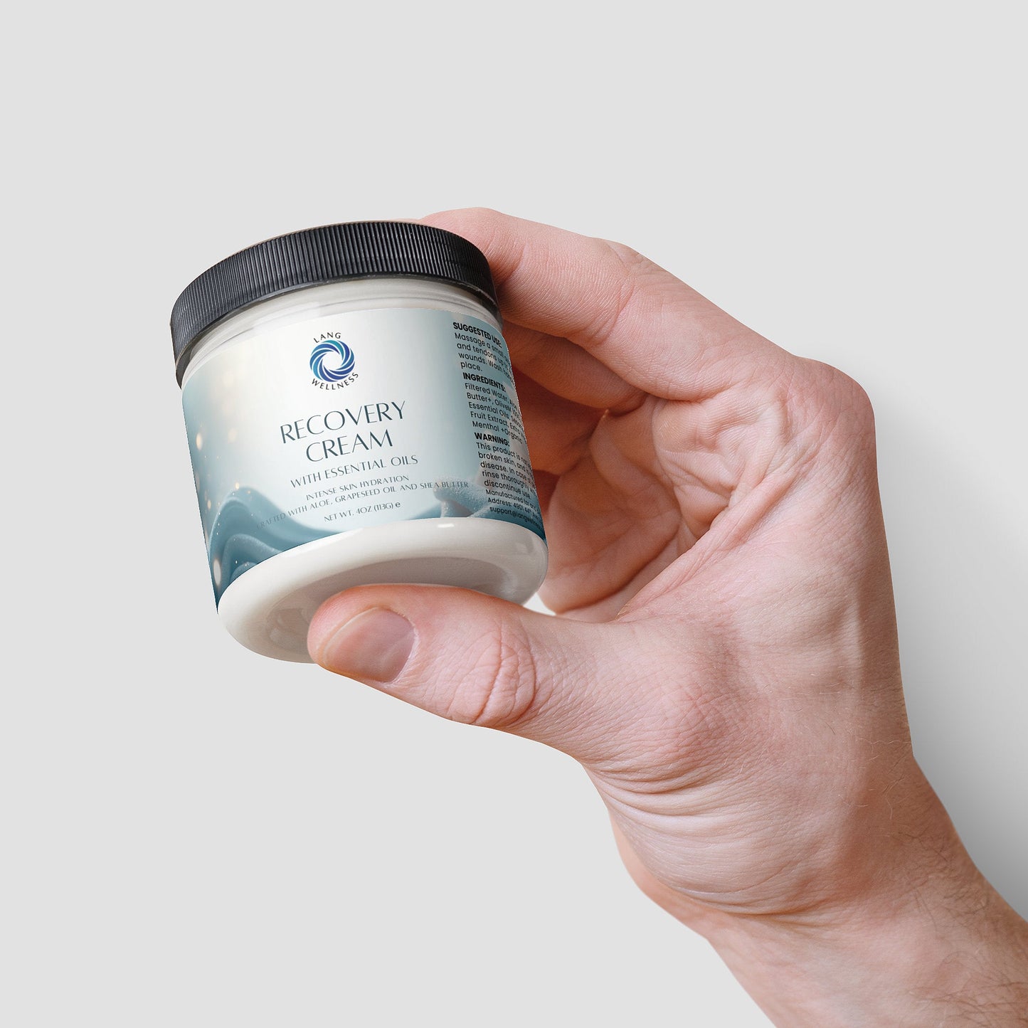 Recovery Cream jar with black lid, teal label, held in hand