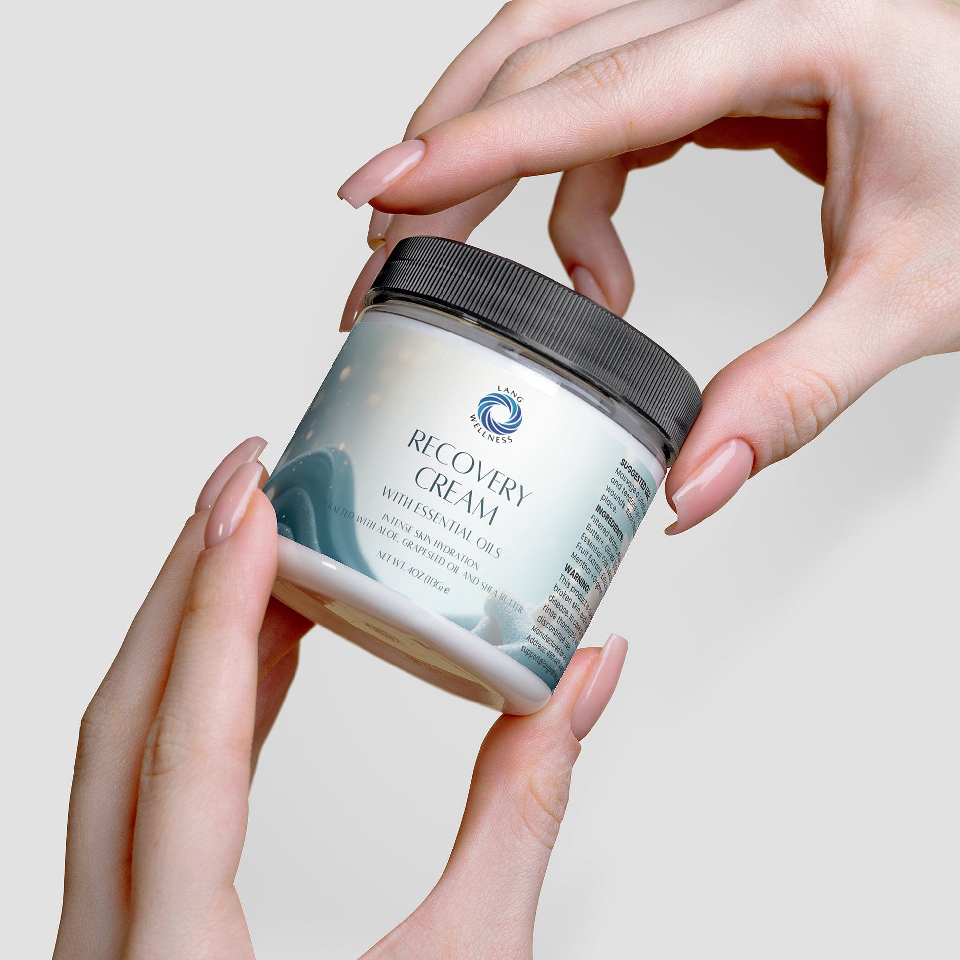 Recovery cream jar held in hands, black lid being lifted off the jar