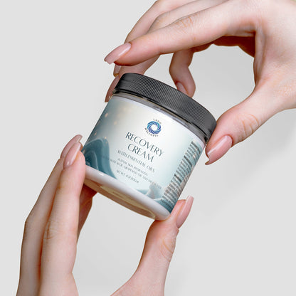 Recovery cream jar held in hands, black lid being lifted off the jar