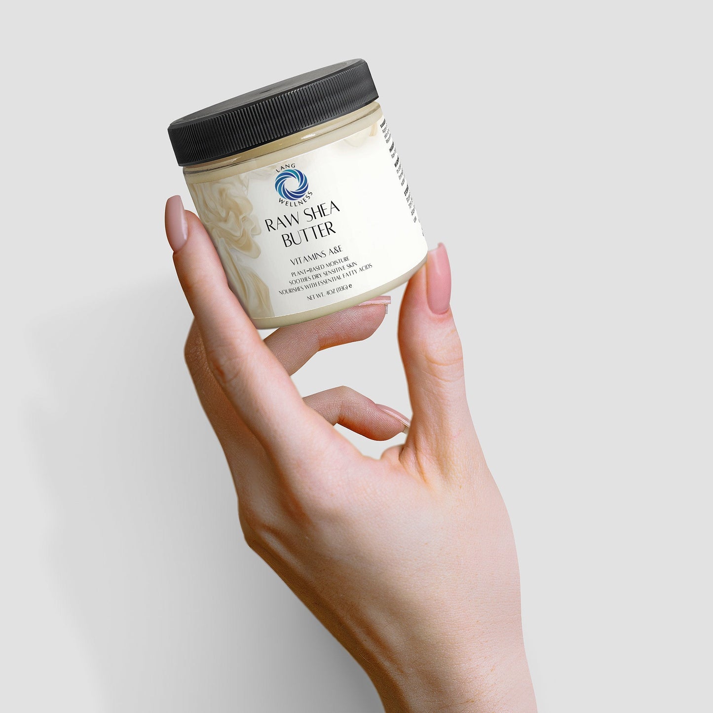 Hand holding an angled shea butter jar with black lid and front label visible