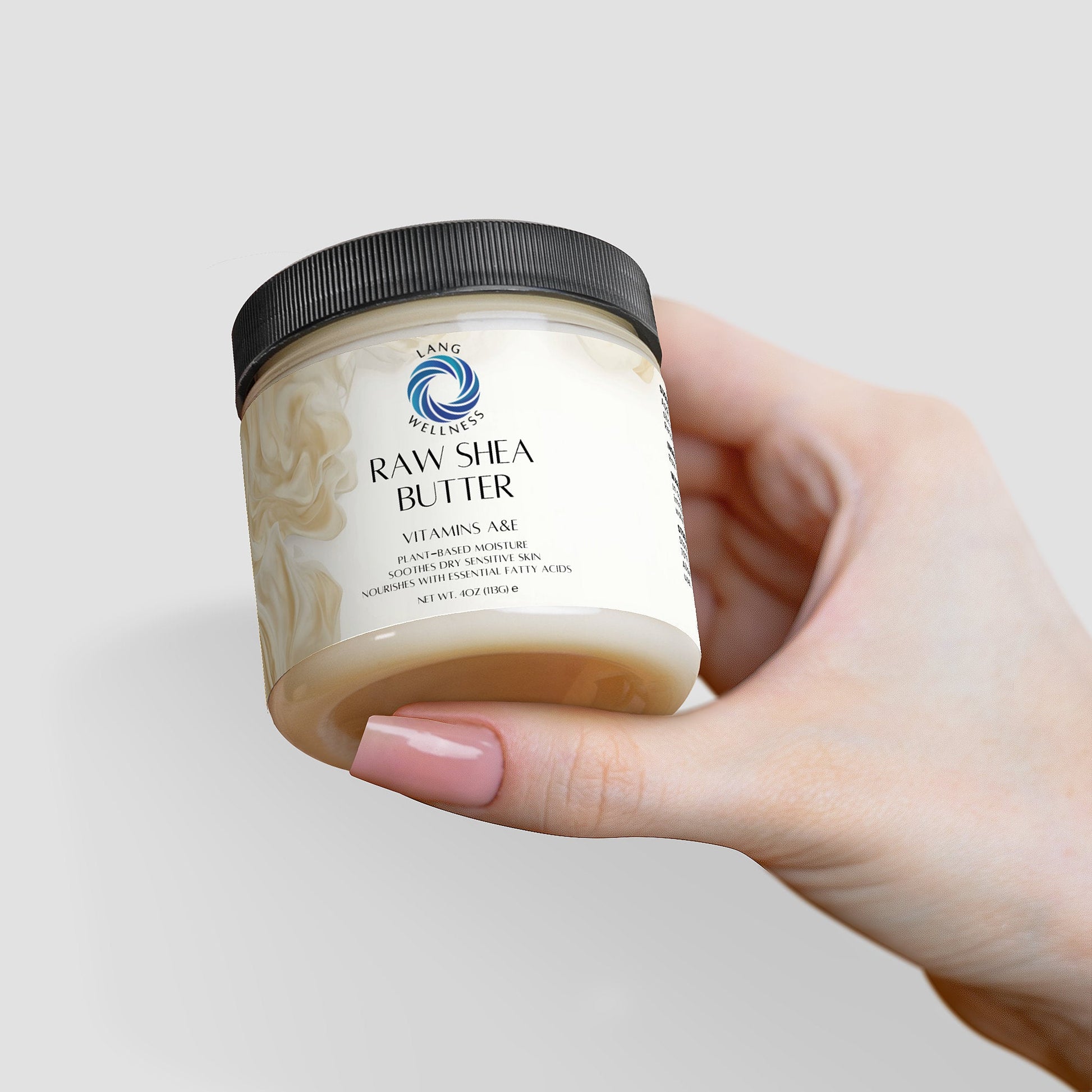 Hand holding a shea butter jar with black lid, label facing forward