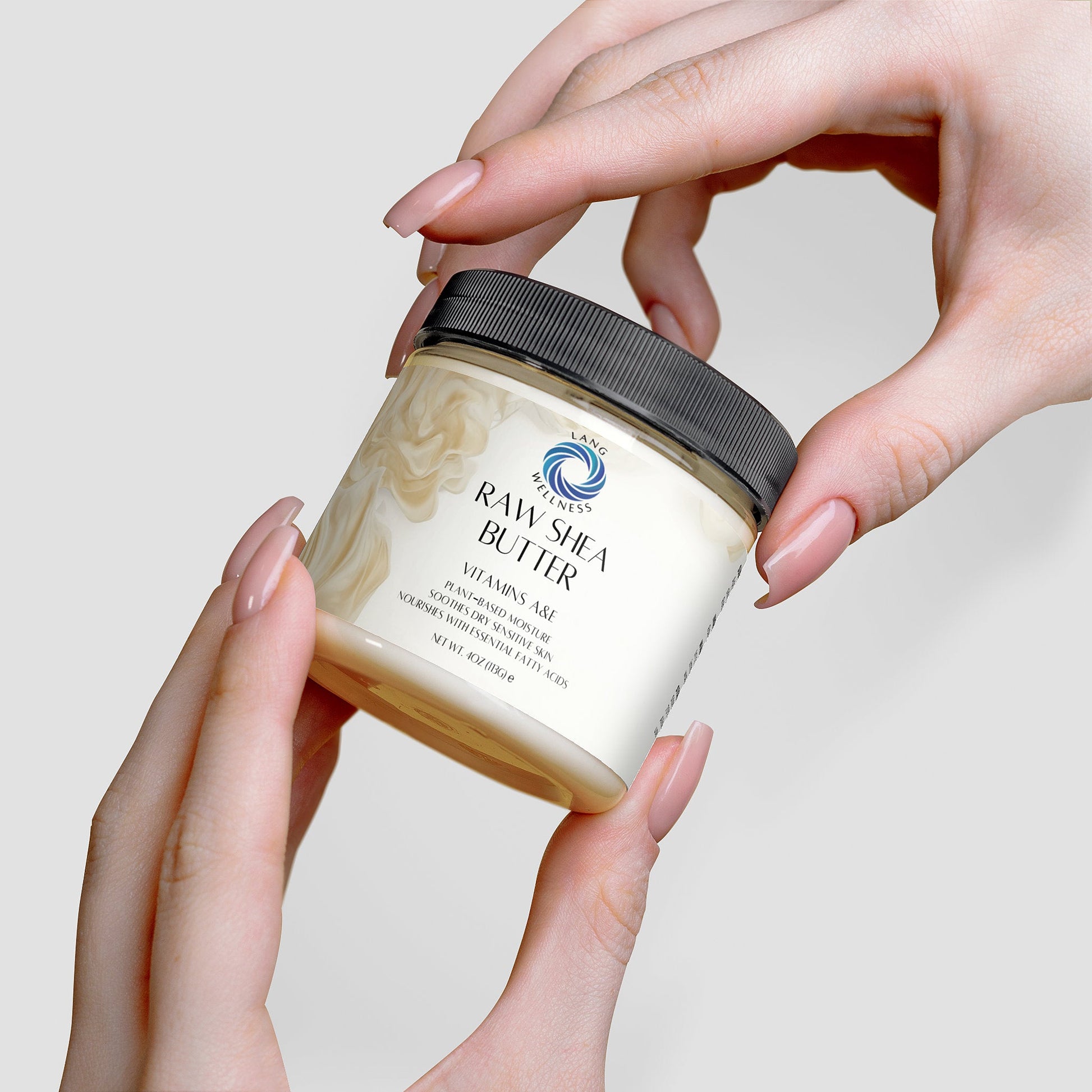 Hands holding a shea butter jar with black lid, product label facing outward