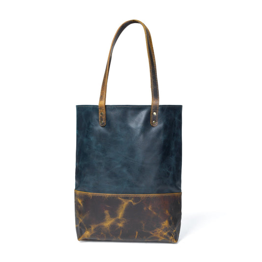 Dark blue leather tote with tan-brown bottom panel, double handles, metal studs