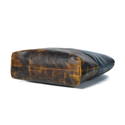 Dark blue leather tote laying on side, tan-brown bottom panel visible
