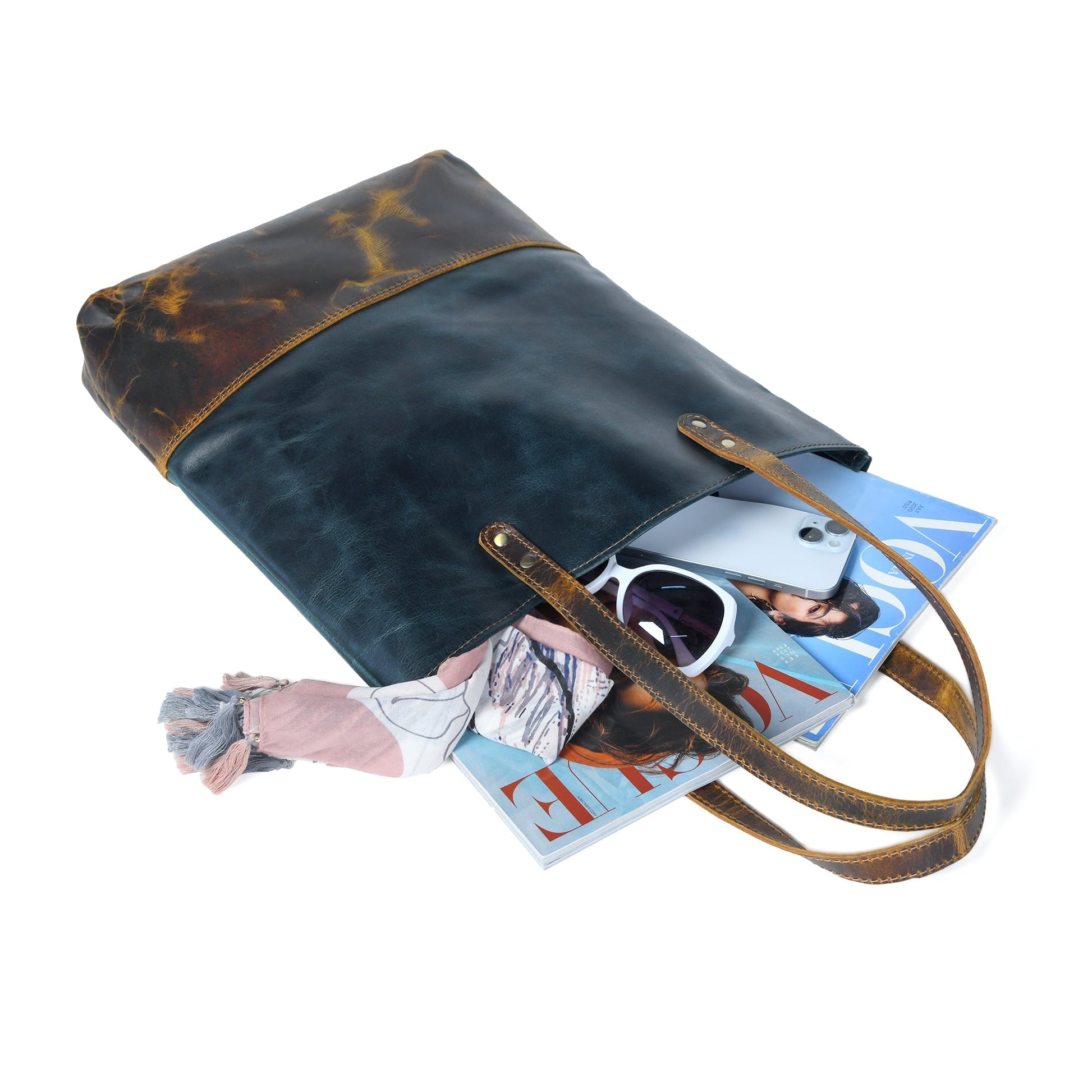 Dark blue leather tote with tan-brown trim, open top with items inside