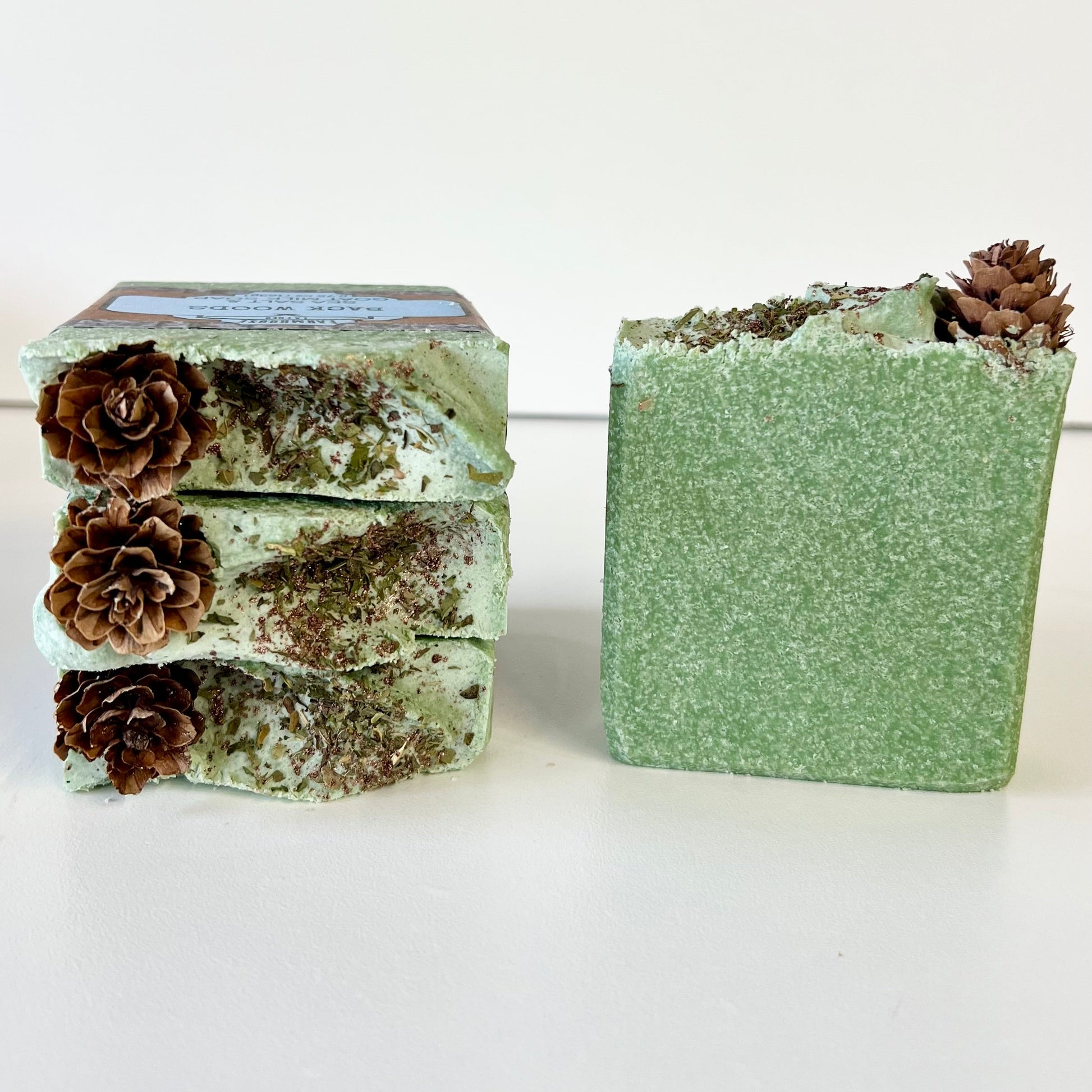 Stacked green sea salt soap bars with pinecone tops, one bar side view