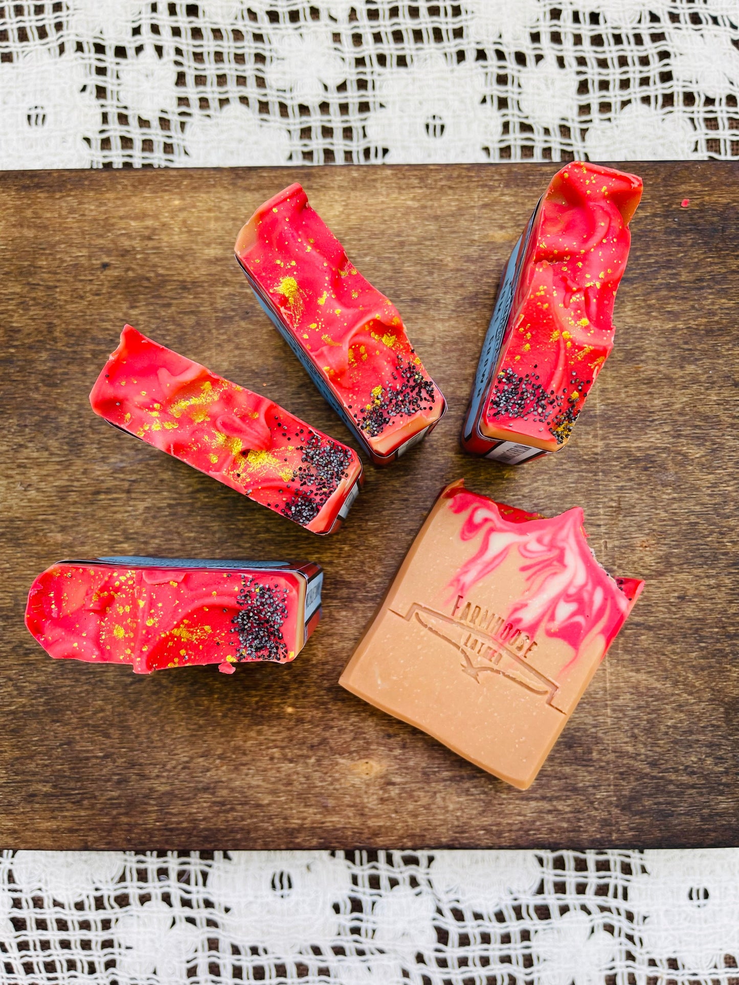 Four red speckled soap bars laid on a wooden board