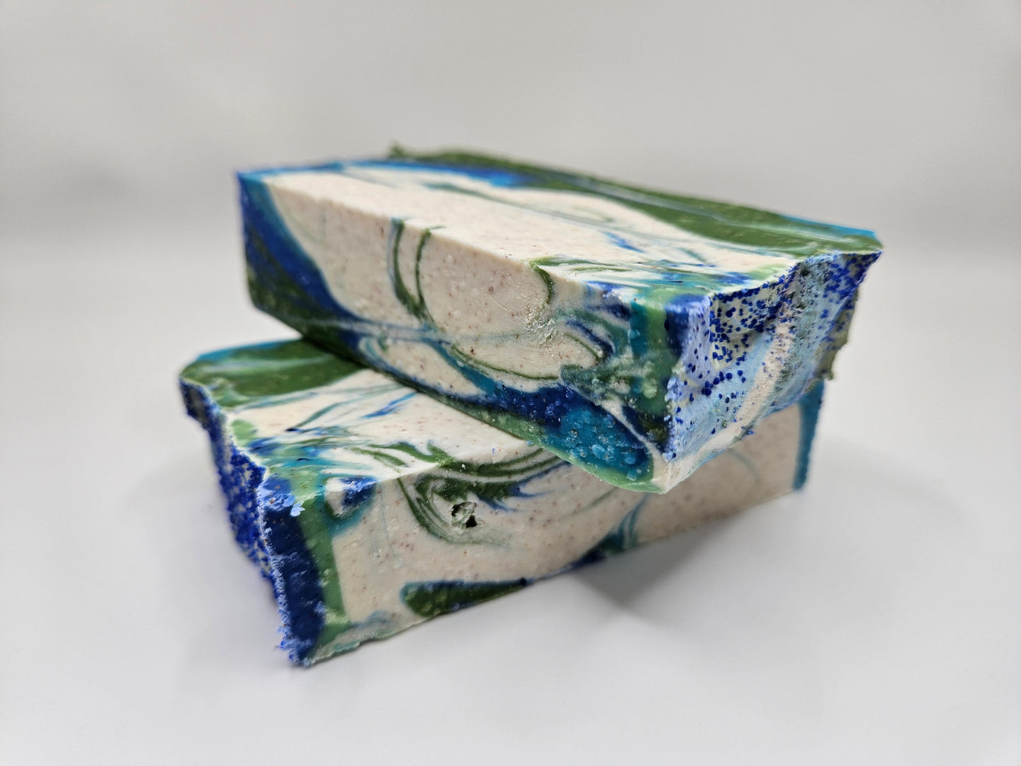 Artisan soap bars with speckled blue-green and white herbal swirl design