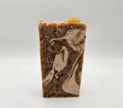 Honey and oatmeal soap bar, dark brown with embedded light swirls and specks