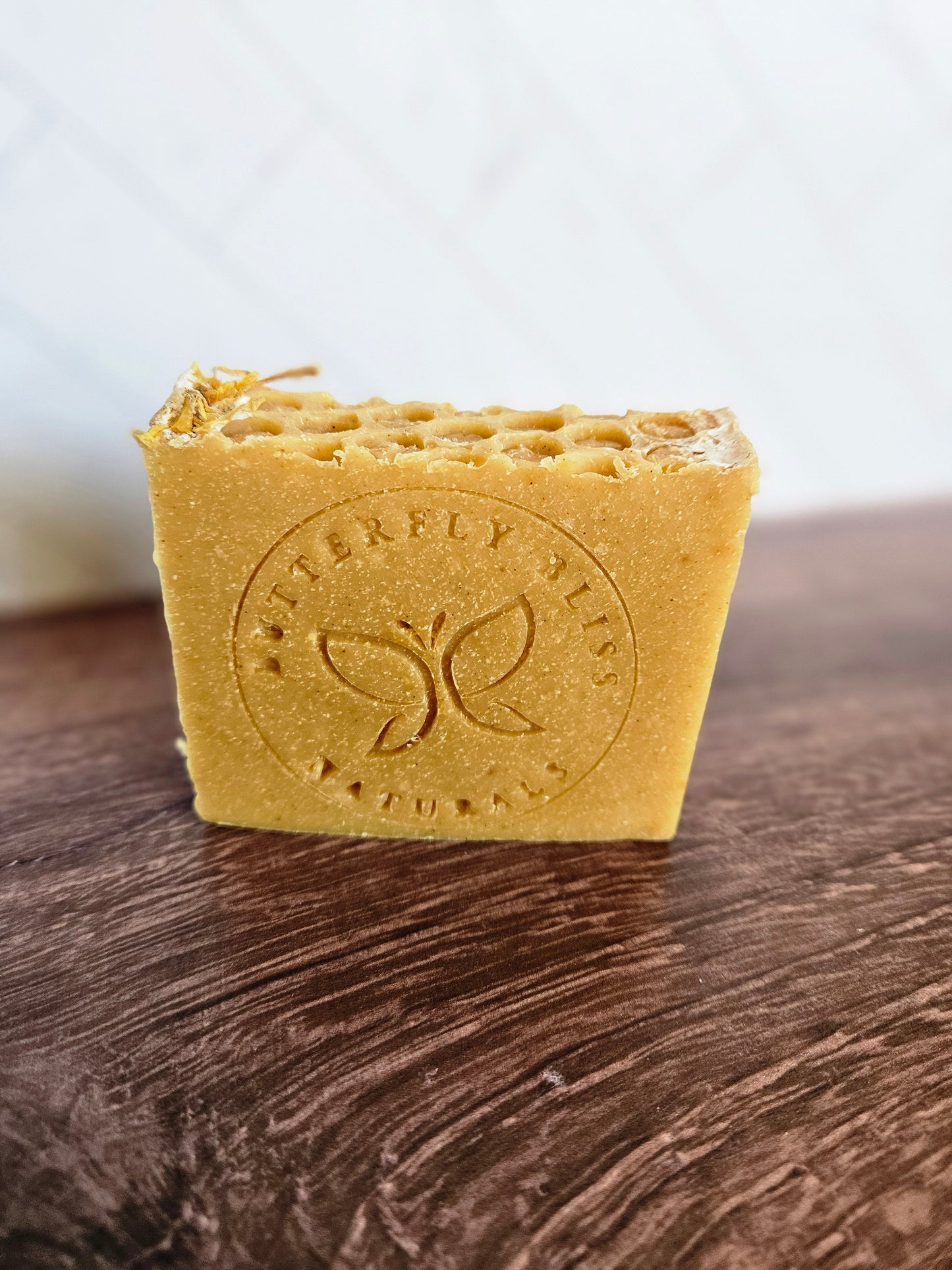 Turmeric and Honey coconut milk soap bar, golden with embossed logo on front.
