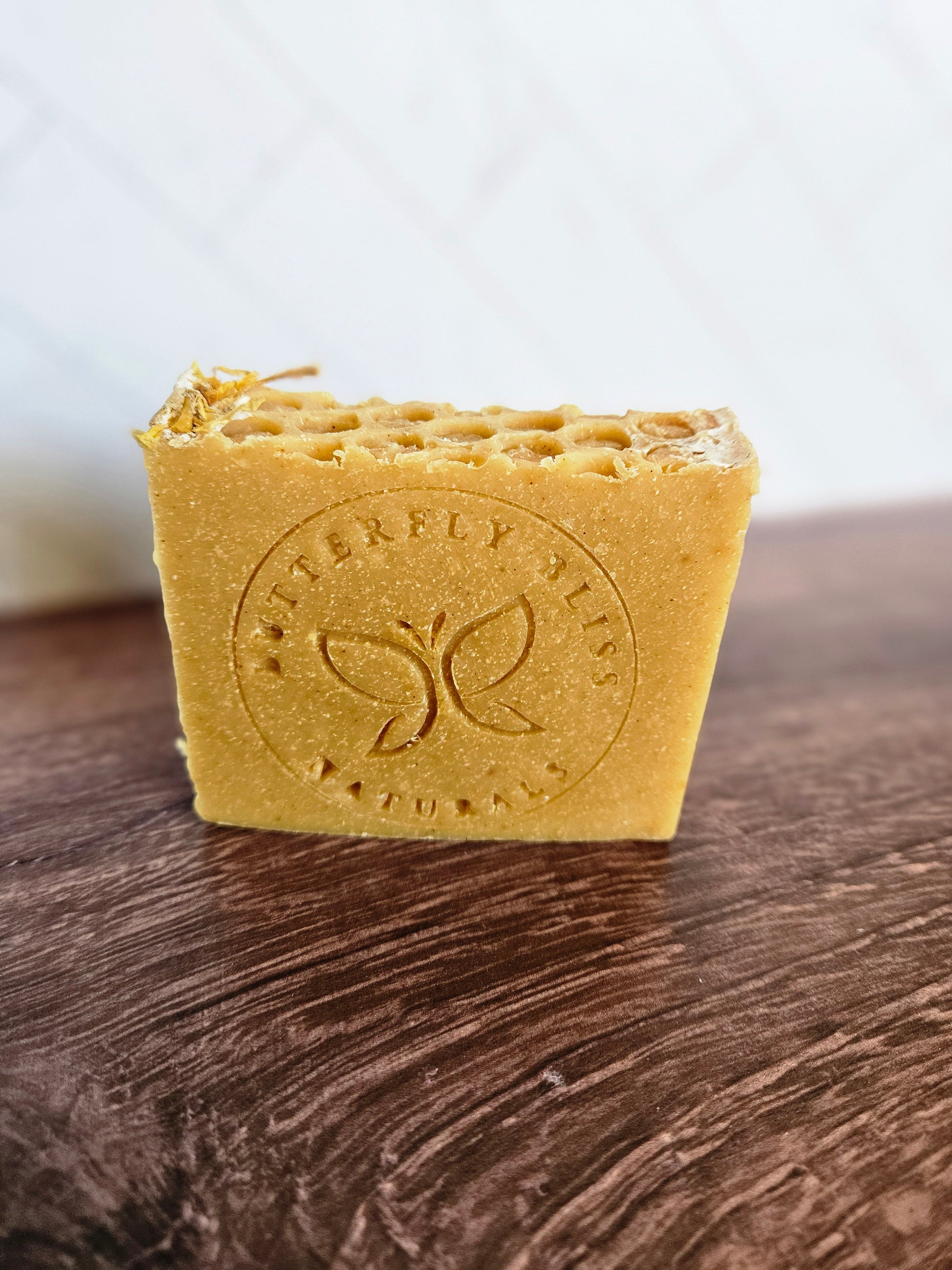 Turmeric and Honey coconut milk soap bar, golden with embossed logo on front.
