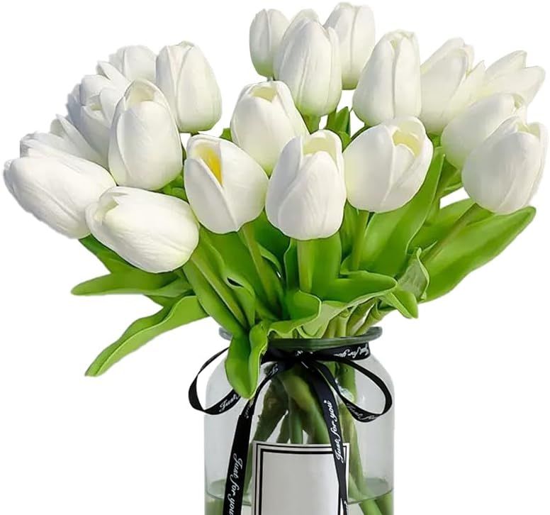 Artificial white tulip bouquet with green leaves in a clear vase, tied with black ribbon