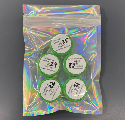Foundation sample set with five circular lids in a green holographic pouch.