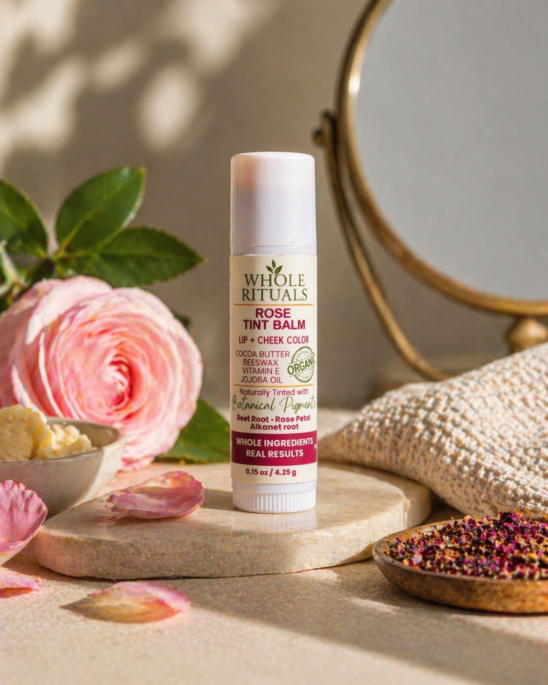 Rose tint balm stick on a stone with pink rose and herbs, for lips and cheeks