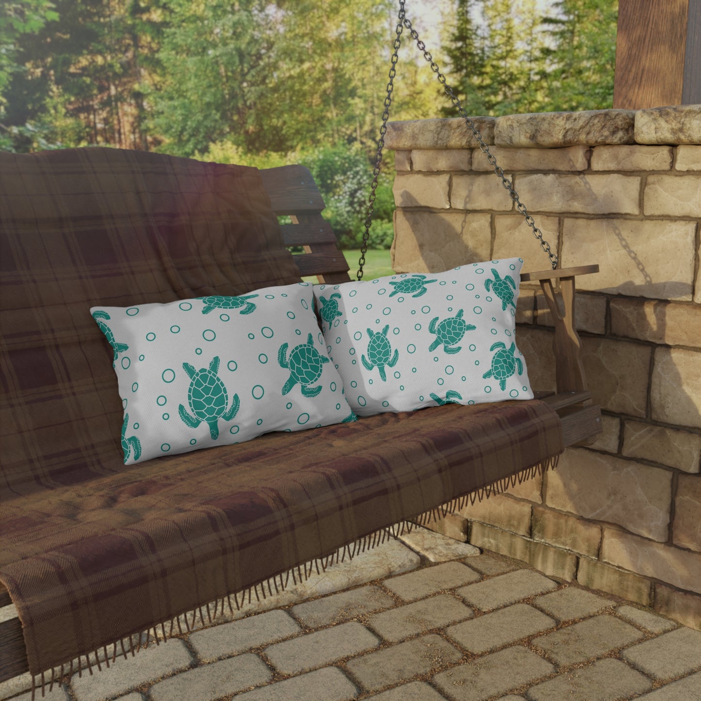 Two outdoor cushion pillows with teal sea turtle and circle ring-dot pattern on white.