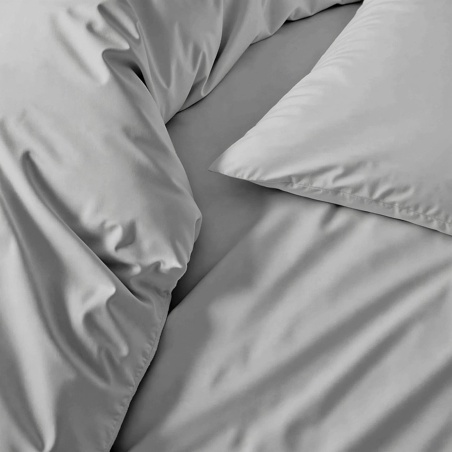 Sateen sheet set in light gray, close-up of smooth bedding fabric