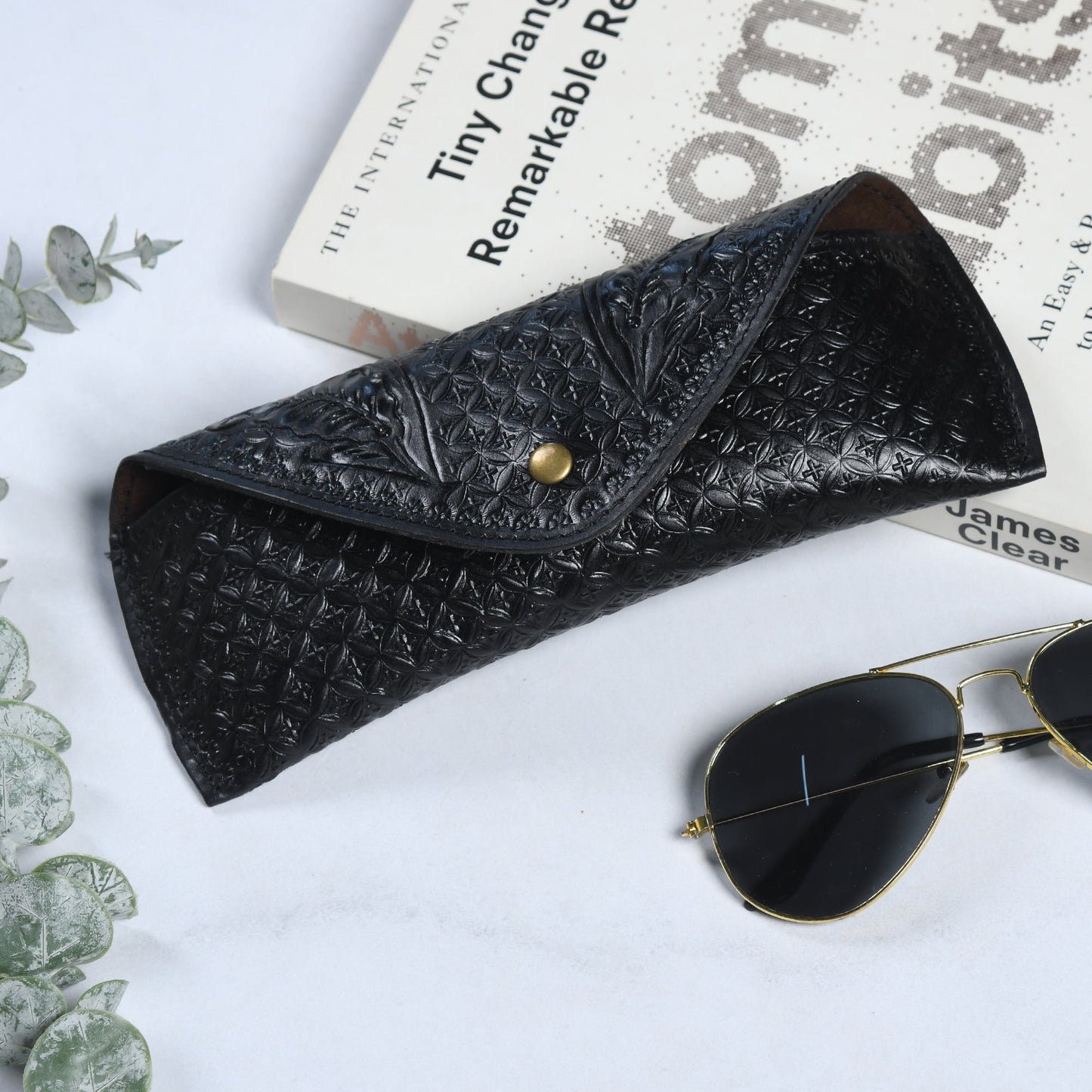 Black textured leather sunglasses cover with snap button closure and curved flap
