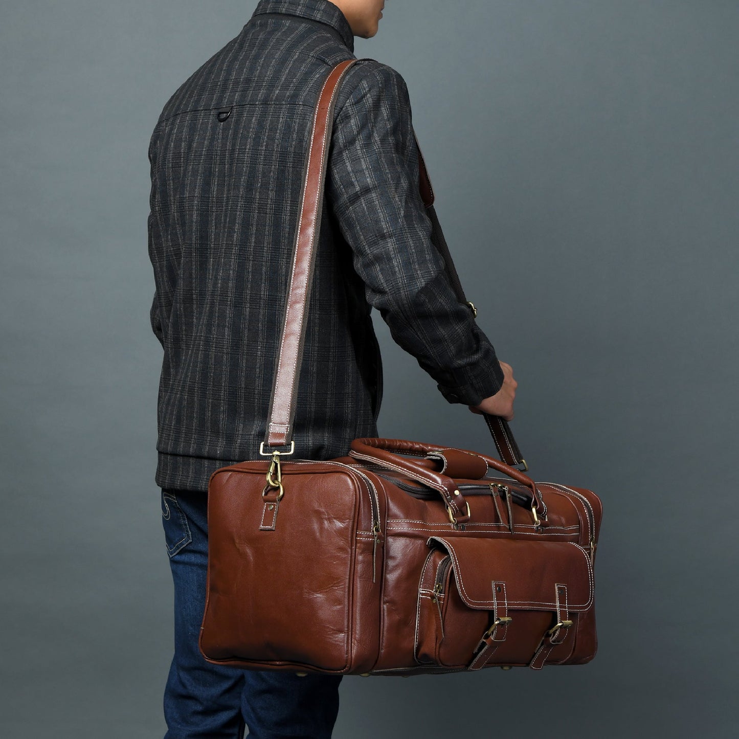 Brown leather weekender duffel carried by shoulder strap with front flap pocket