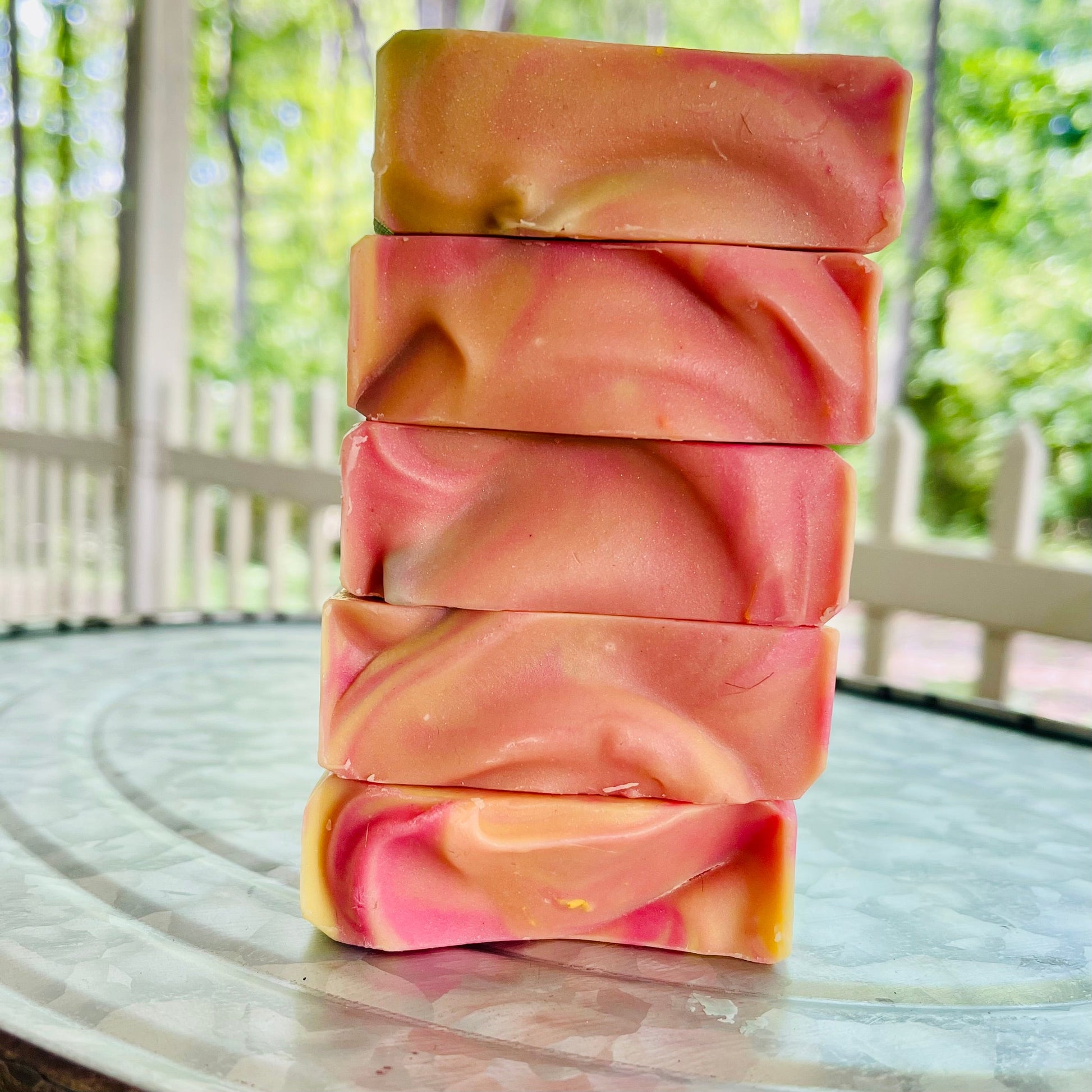 Stacked soap bars in orange, pink, and teal with marbled swirl pattern.