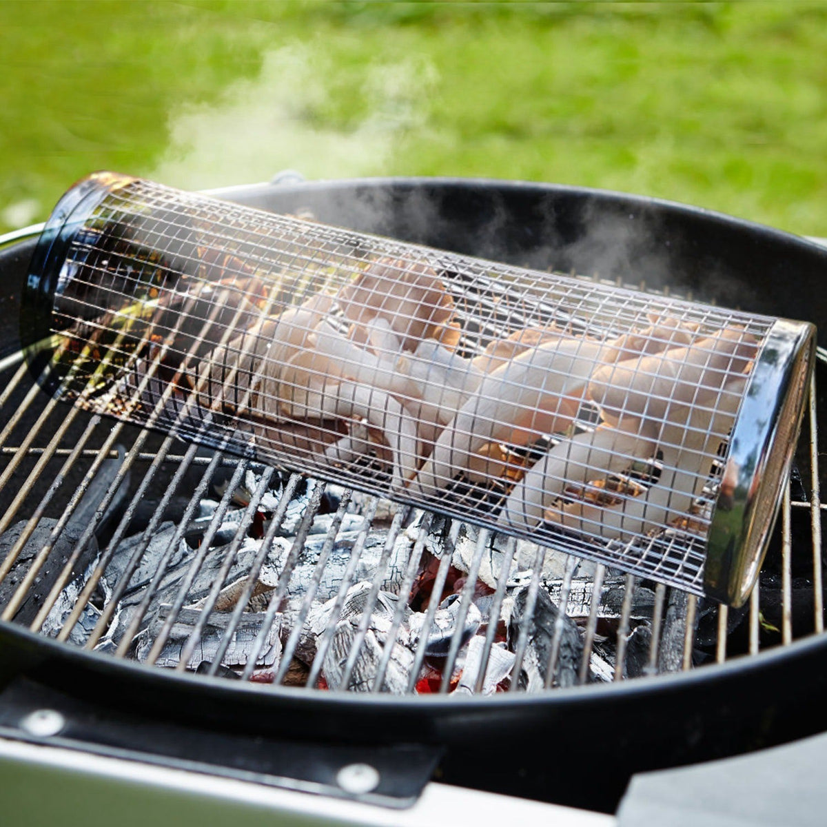 Cylindrical mesh grill basket set on barbecue grate with corn and meat