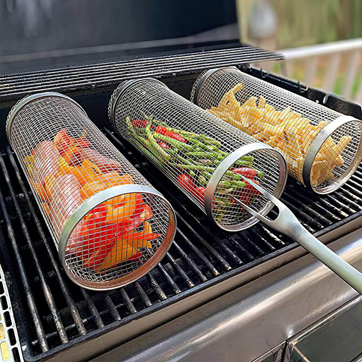 Four cylindrical mesh grill baskets on a barbecue grate with assorted food