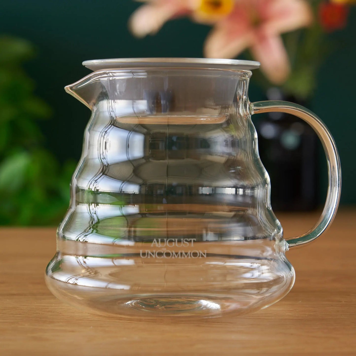 Clear glass two-cup teapot with curved handle and spout, empty interior.